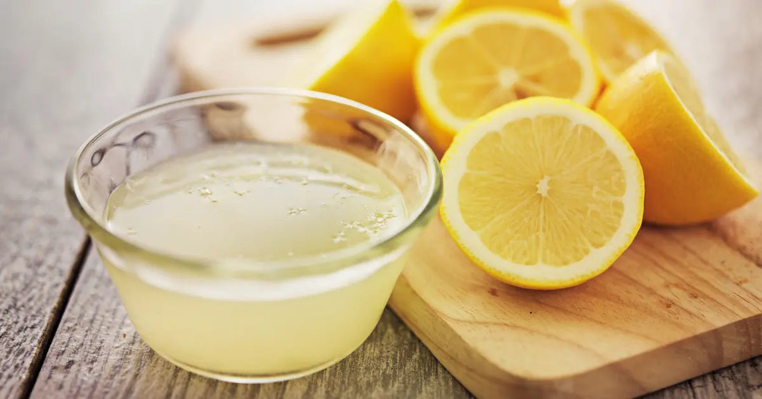 cold-pressed lemon juice in a glass bowl with freshly cut lemon halves on a wooden board