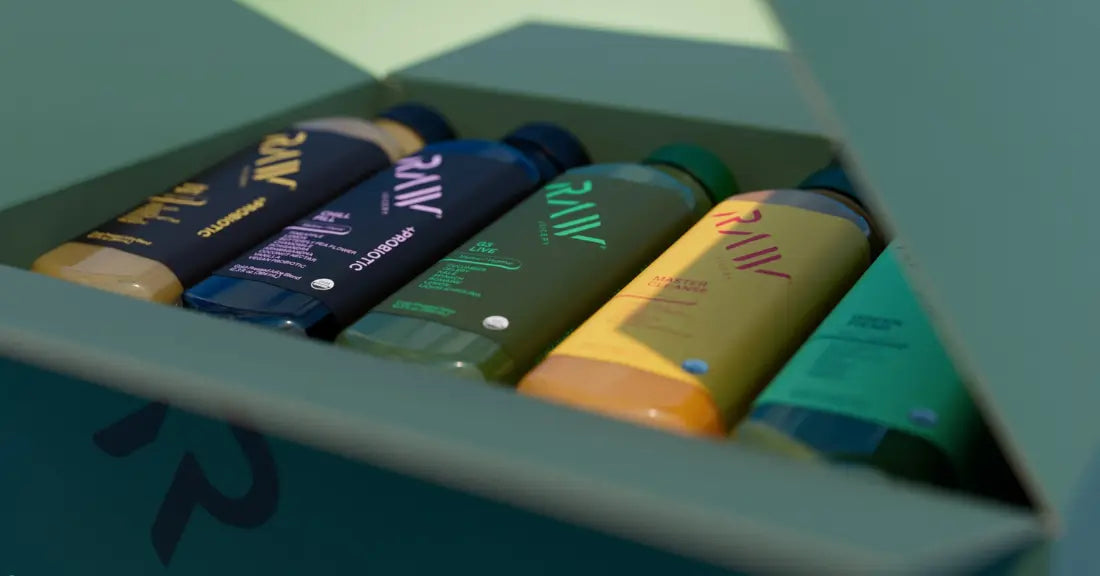 Certified organic juices in a green box, featuring various flavors in colorful bottles with RAW branding